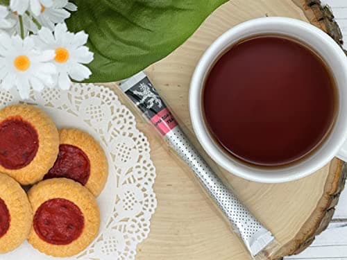 Amazon Fruit Tea — on wood slice beside white cup of brewed tea, jam thumbprint cookies, white daisies