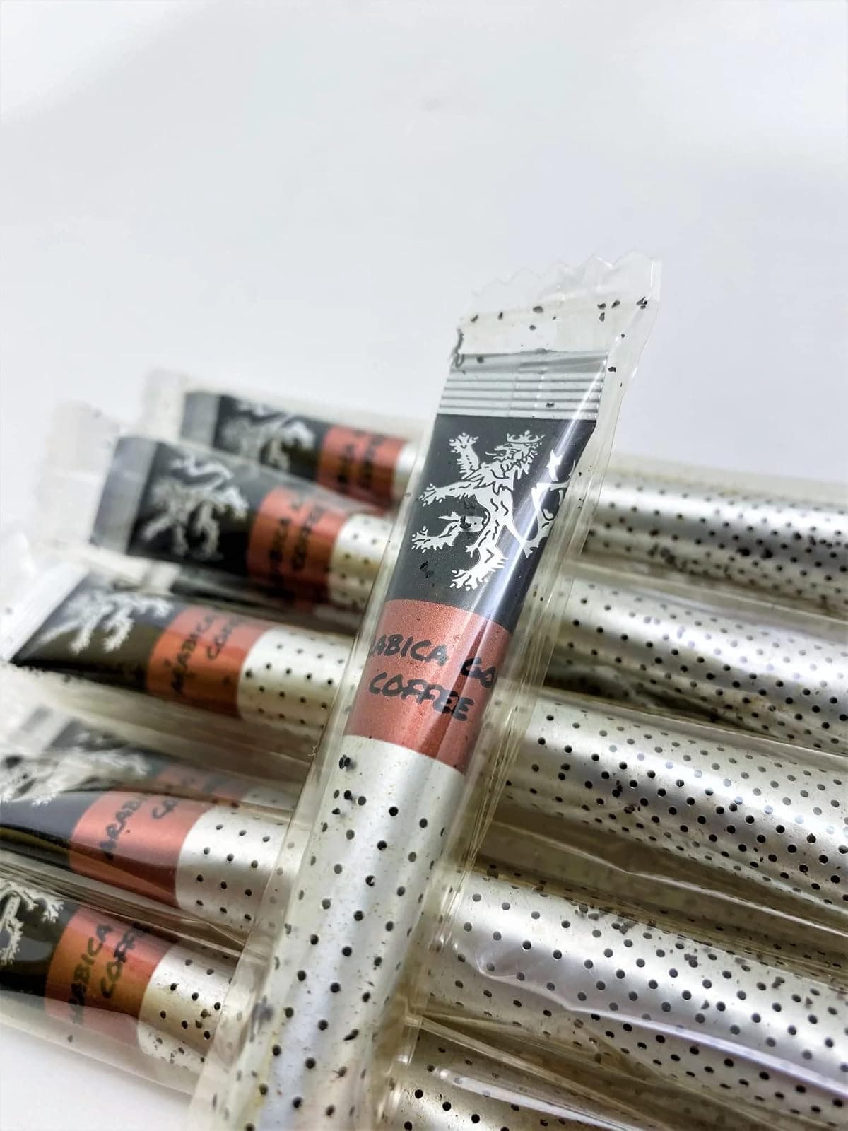 Arabica Gold Instant Coffee sticks in their individual wrappers on a plain background