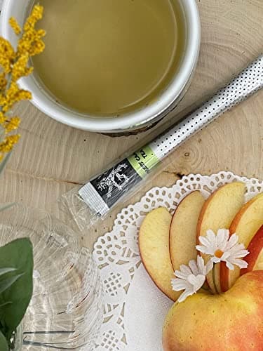 Cypress Chamomile Tea — on wood board beside mug of pale brewed tea, apple slices, daisy, goldenrod flowers, glassware