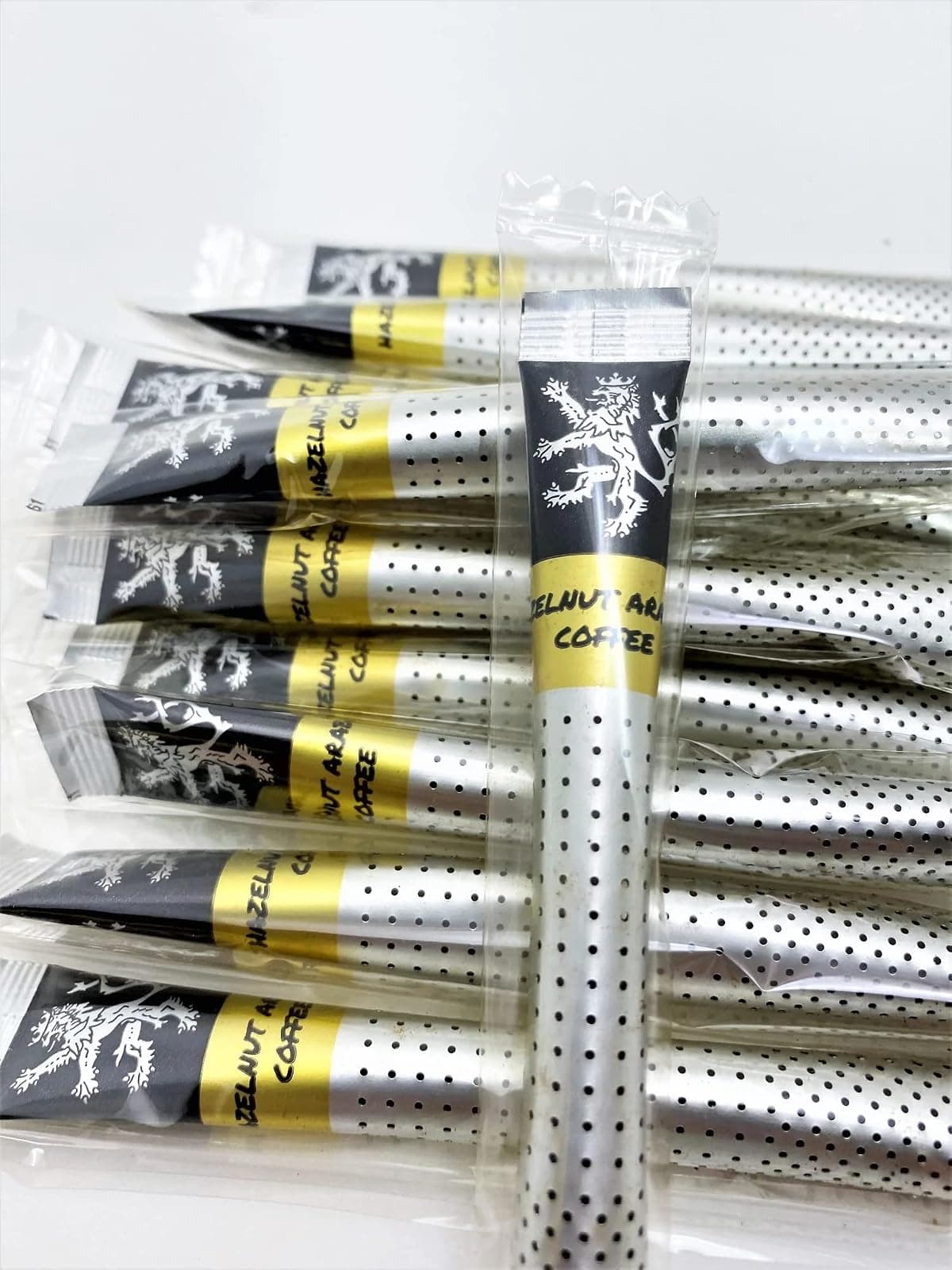 Hazelnut Arabica Gold Instant Coffee sticks in their individual wrappers on a plain background