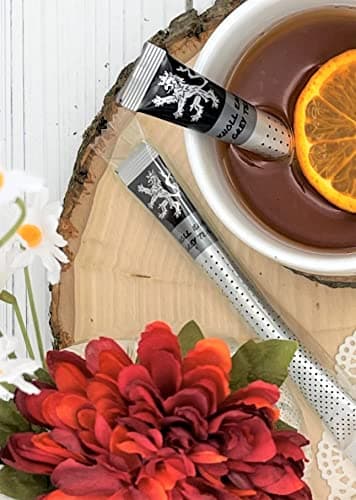 Knoll Earl Grey Tea — two wrapped sticks on wood slice, white cup of brewed tea with orange slice, daisies, red and orange flowers