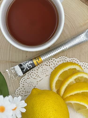Lucky Lemon Tea — on wood board and doily beside white cup of brewed tea, lemon wheel slices, whole lemon, daisies
