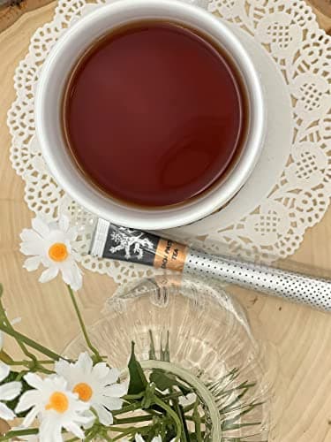 Peach Passion Tea — on wood board and doily beside white cup of brewed tea, white daisies, glassware