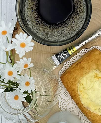 Vanilla Arabica Coffee — on wood board beside dark glass mug of coffee, white daisies, glass vase, slice of cake and pastry, doily